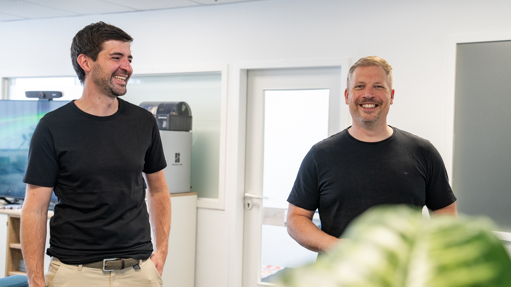 Zwei Kollegen der OIT GmbH lachen im Büro in Osnabrück