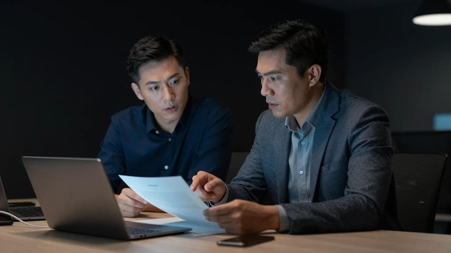 Zwei IT-Berater besprechen SharePoint Berechtigungen verwalten anhand von Unterlagen im Büro
